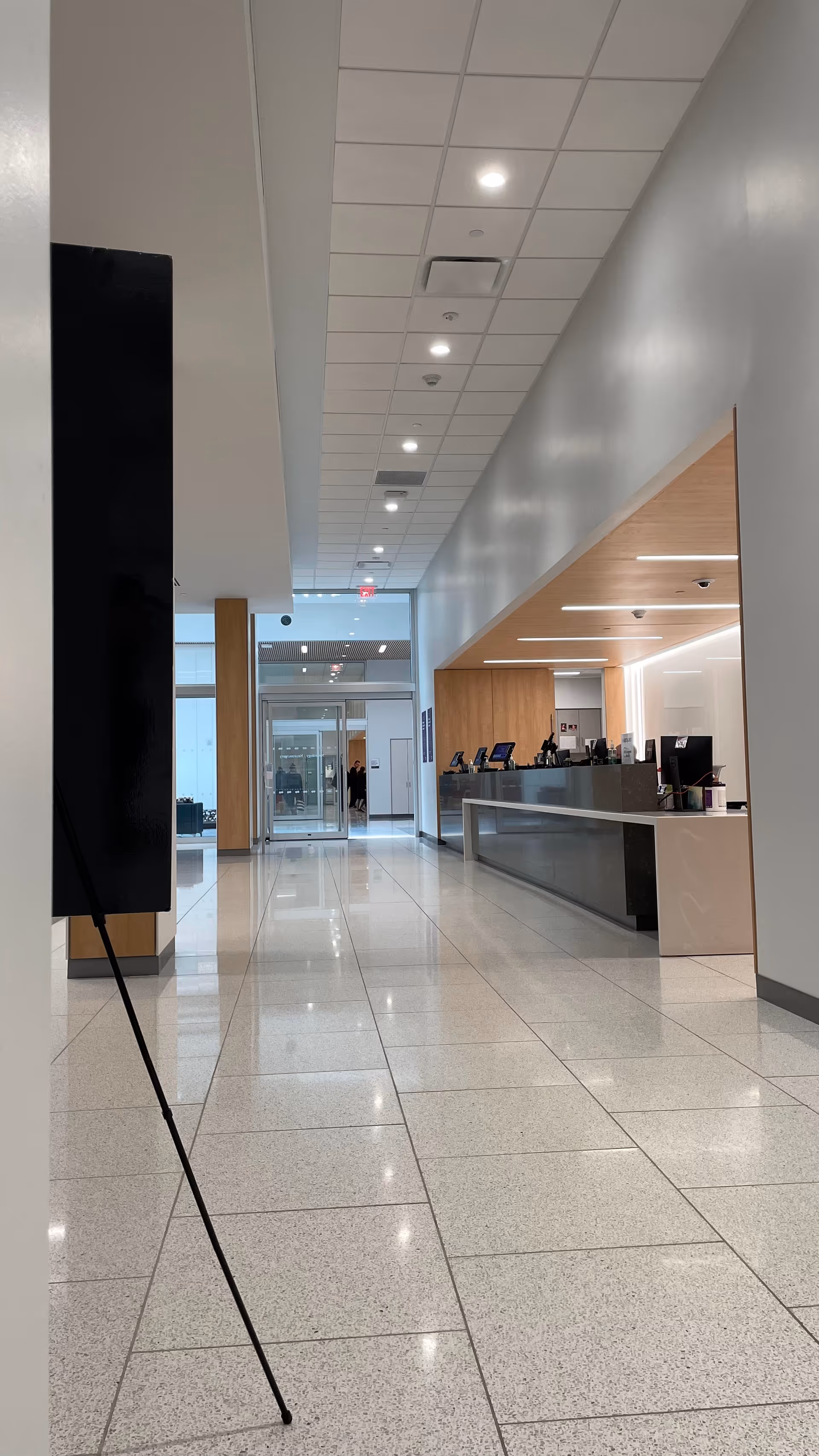 Bright, modern ambulatory care lobby hallway with a long reception desk and glass doors.