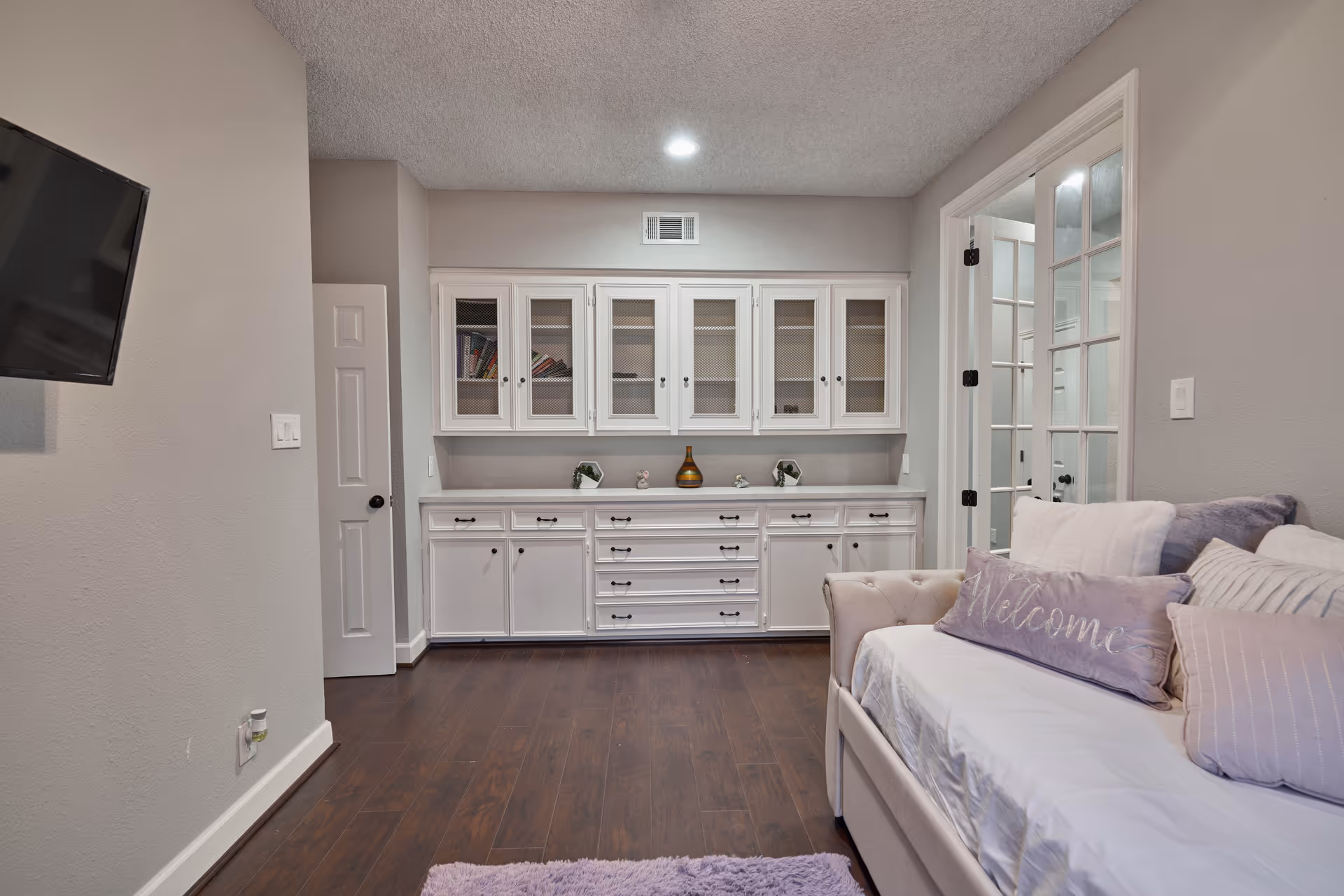 Cozy living room with white cabinets, a sofa, and wall-mounted TV.