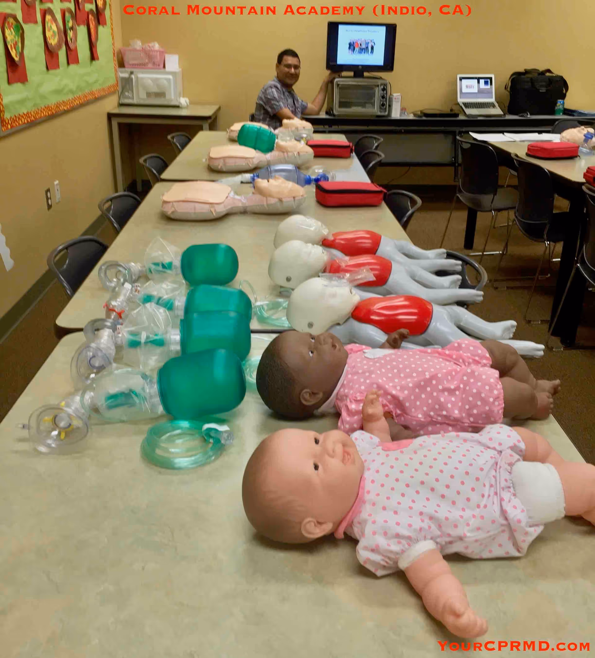 Infant CPR mannequins and equipment laid out on tables in a training room