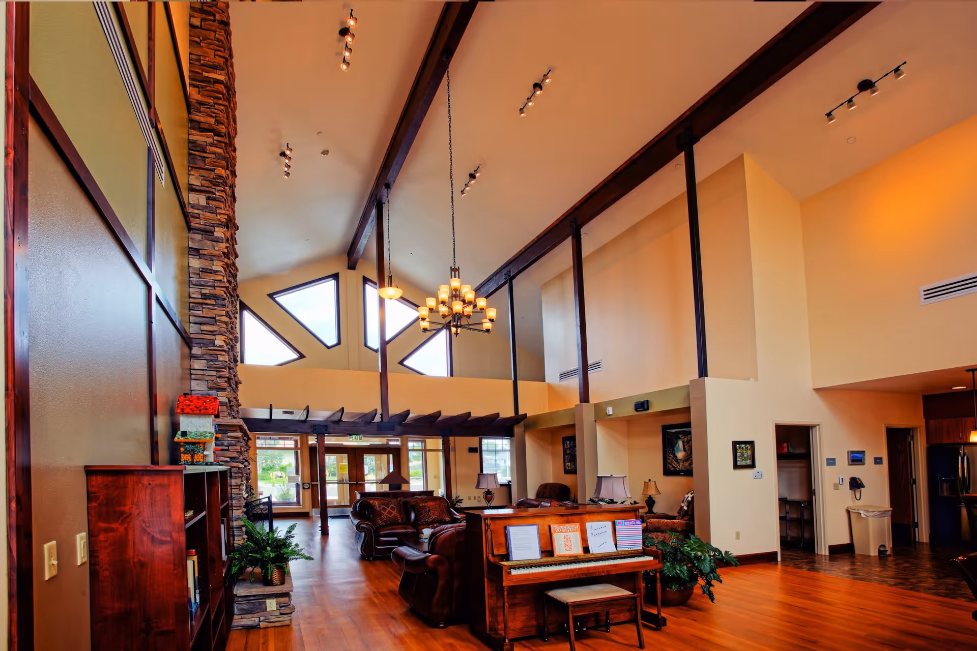 Vaulted interior lobby with stone fireplace, wooden floors, chandeliers, and seating.