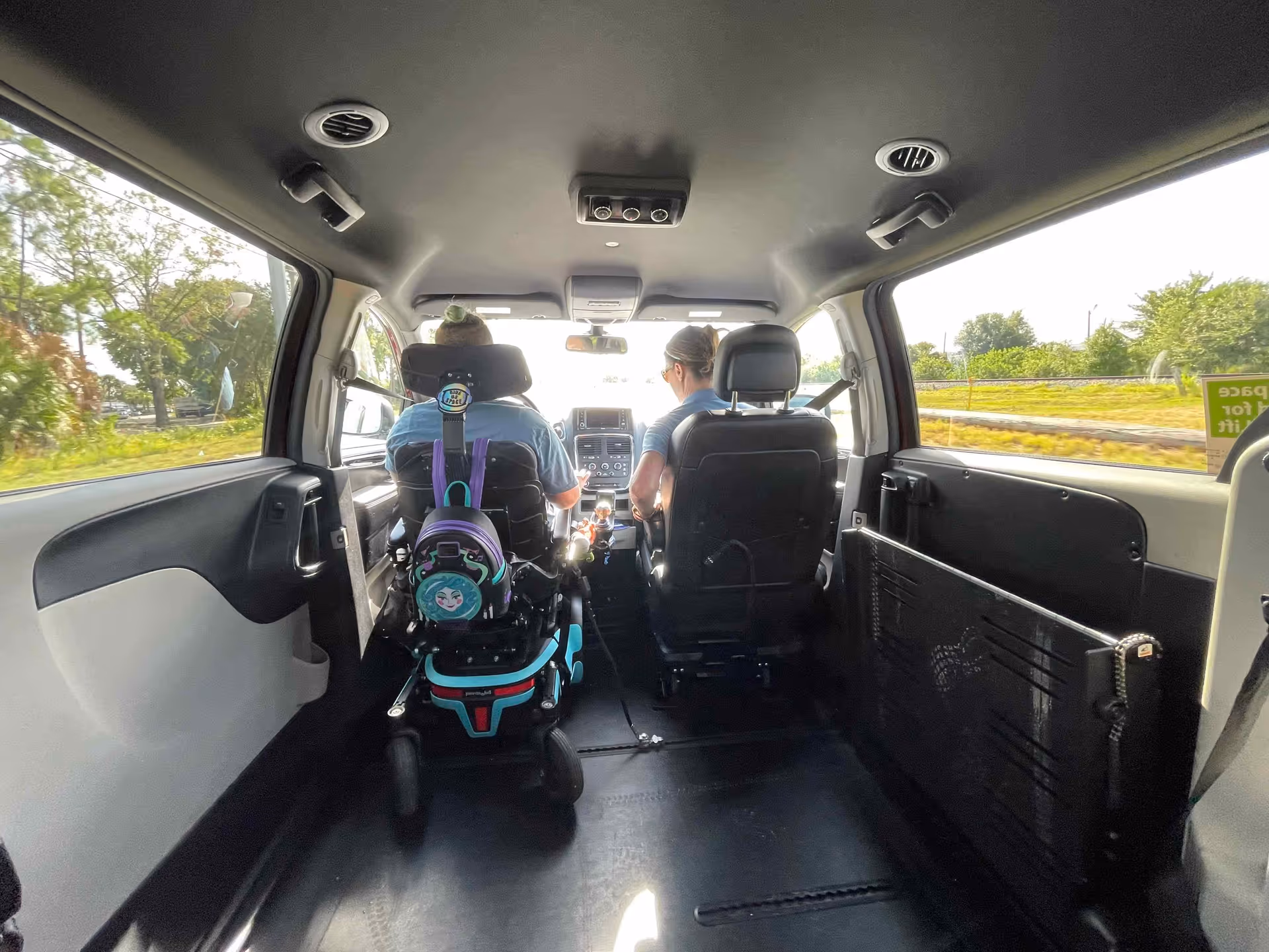 Interior of a mobility van with two passengers seated toward the front.