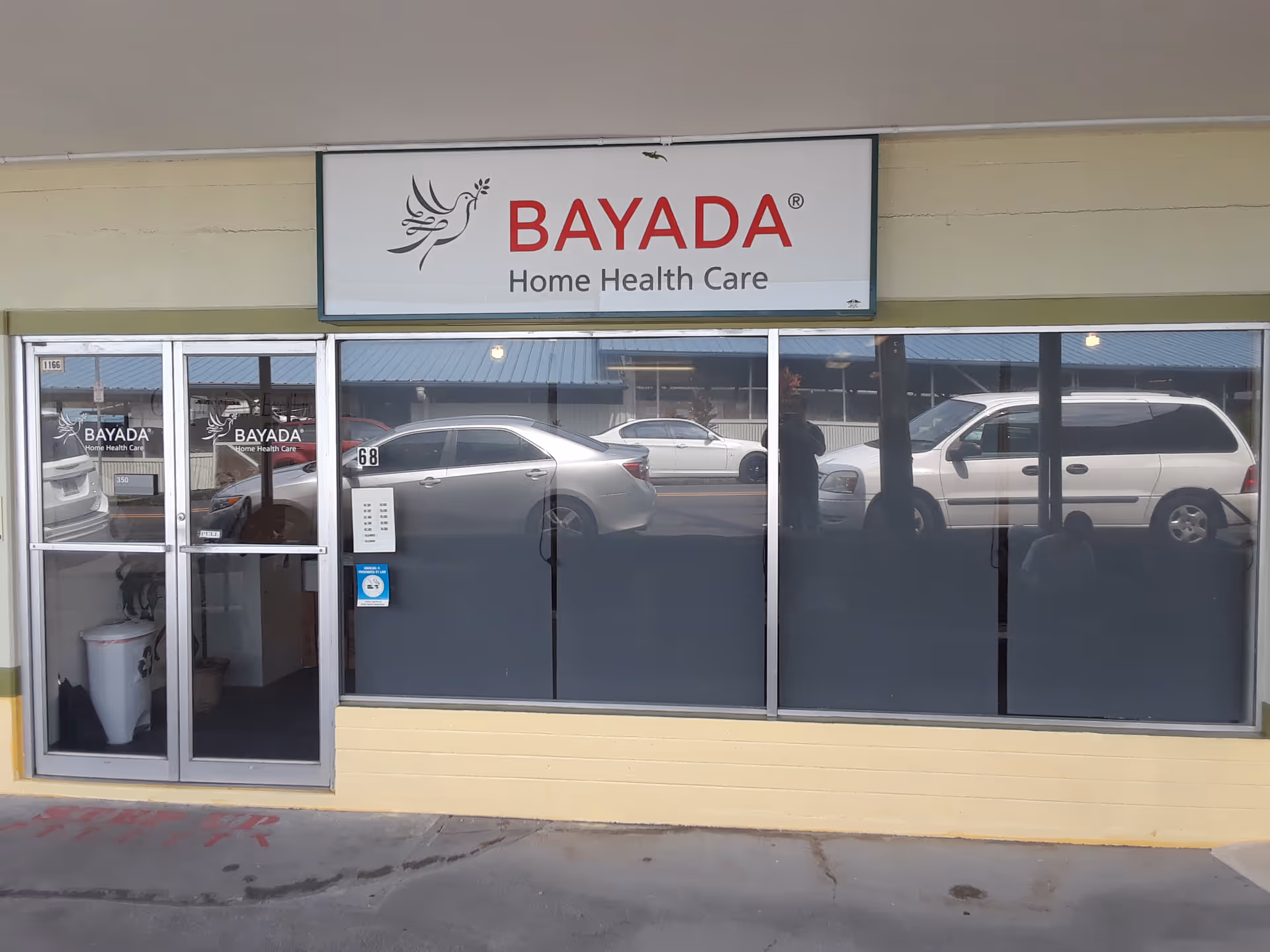 BAYADA Home Health Care storefront with glass doors and windows, reflecting parked cars.