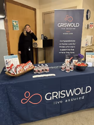 Indoor facility lobby with a Griswold Home Care banner, table, and a staff member present.