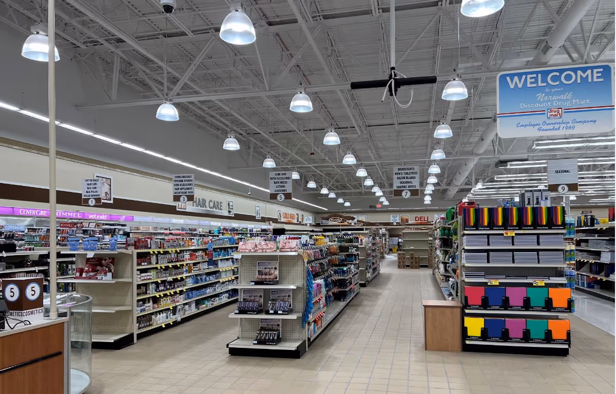 Well-lit Discount Drug Mart interior with long aisles, shelves of products, and a welcome sign.