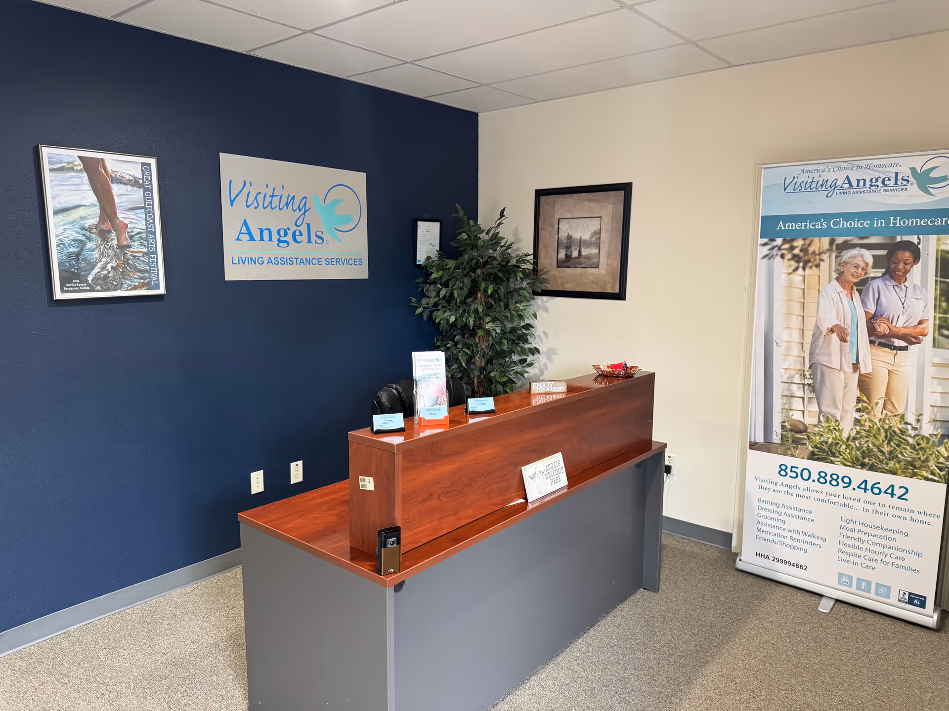 Reception desk in Visiting Angels lobby with signs and a banner.