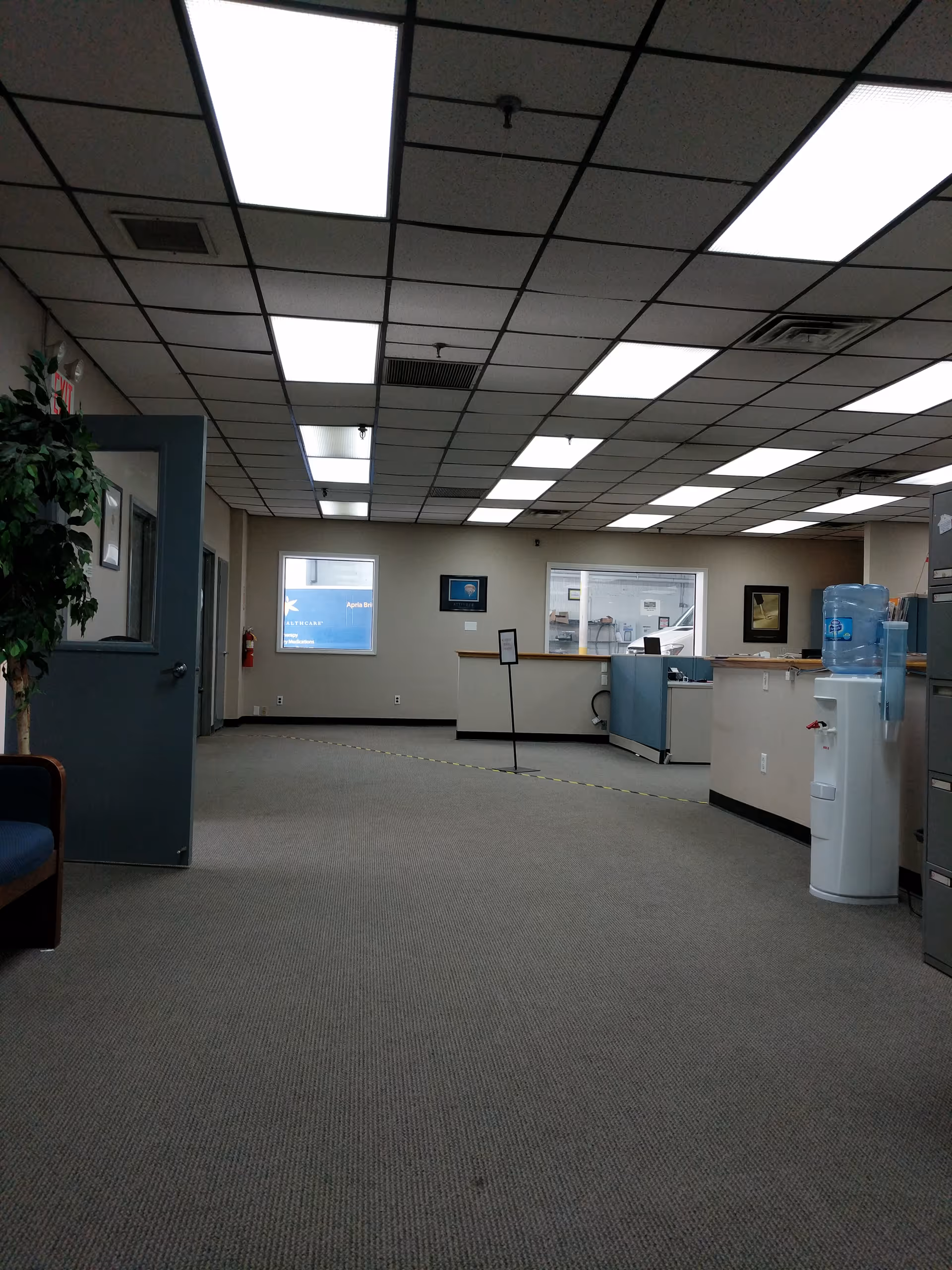 Spacious interior lobby with reception desk, water cooler, and bright fluorescent ceiling lights.