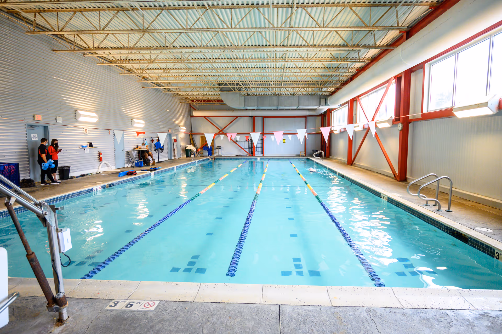 Indoor pool with lane markers and flags inside a therapy facility.