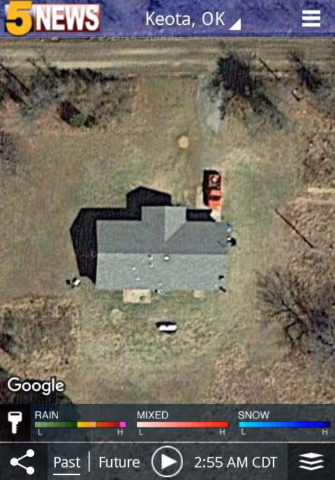 Aerial view of a single-story house with driveway and a red vehicle in a grassy yard.