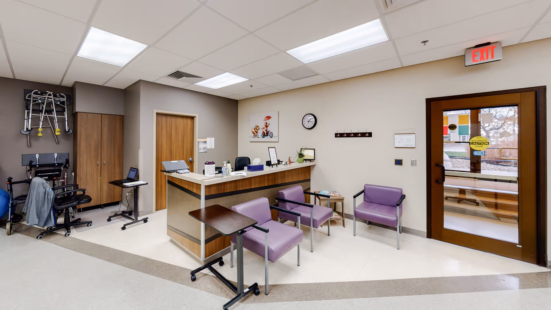Lobby reception area with purple chairs, a front desk, and an exit door.