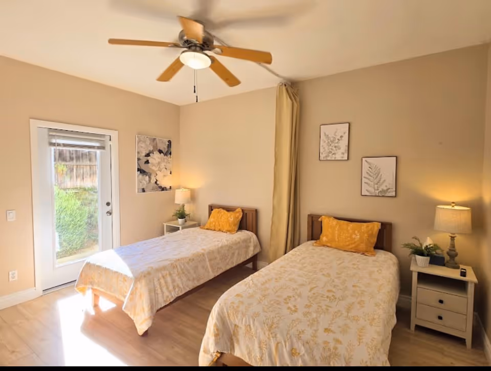 Two twin beds with matching bedding and nightstands in a bright beige bedroom.