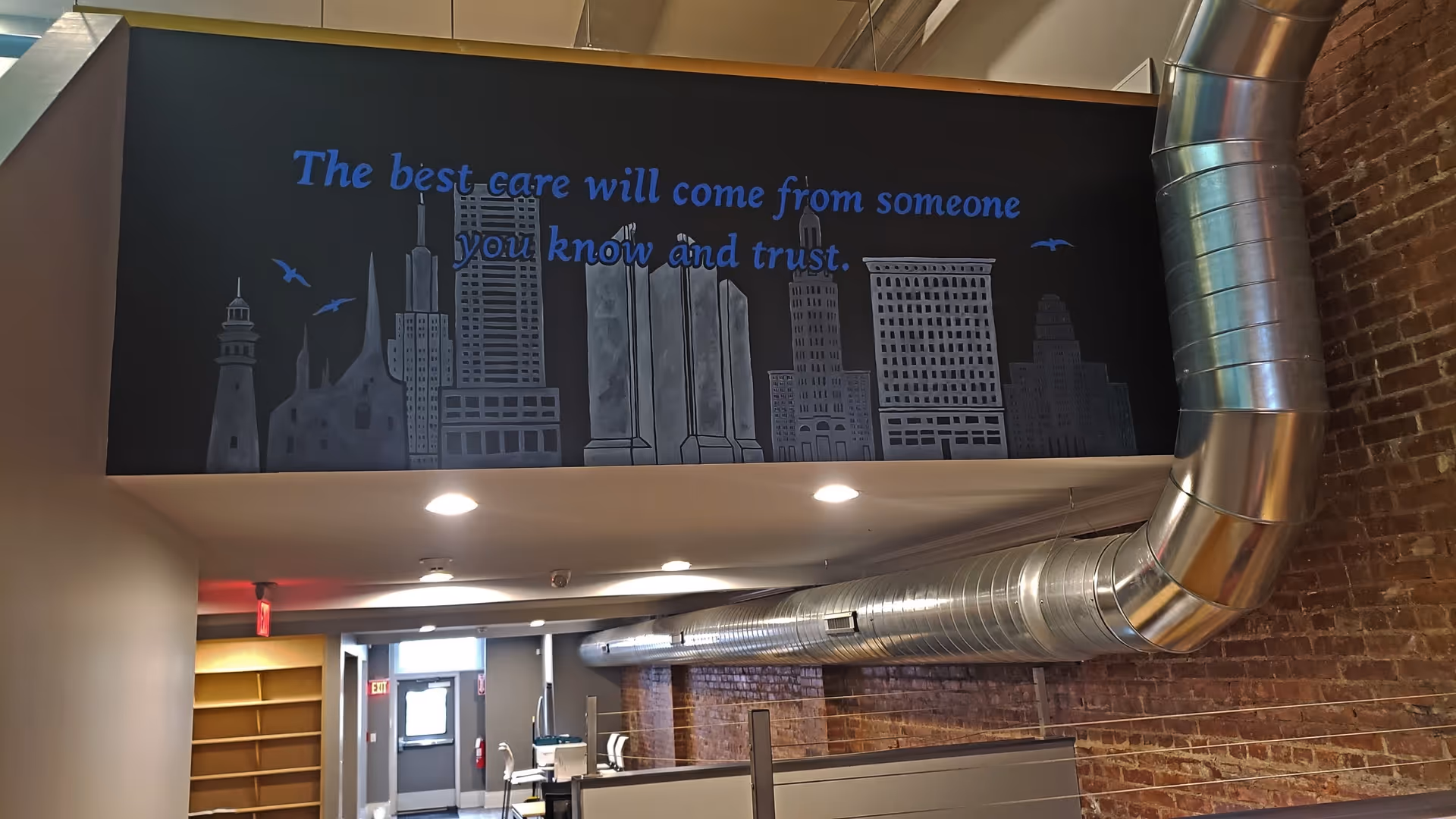 Interior corridor featuring brick wall, exposed ductwork, and a skyline mural.