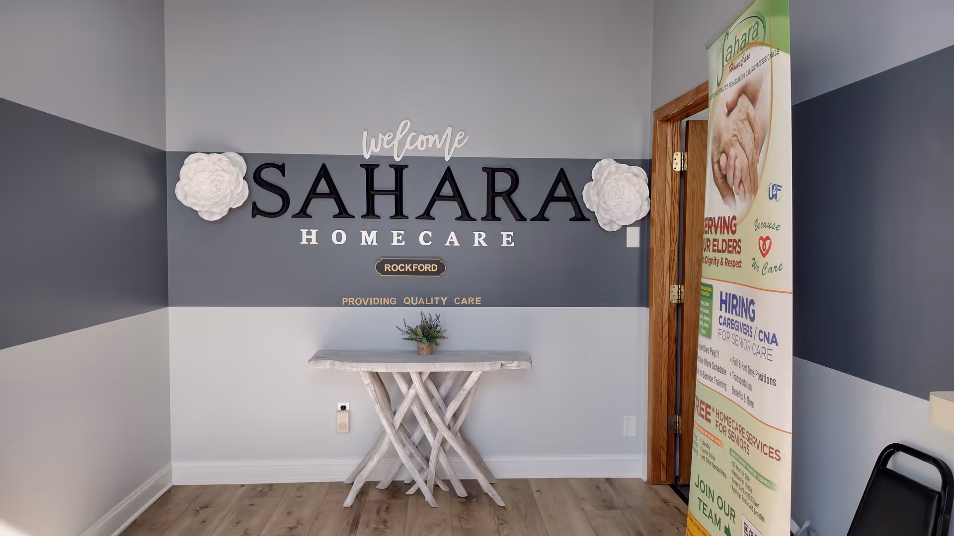 Lobby area with Sahara HomeCare sign and a small table against a blue-gray wall.
