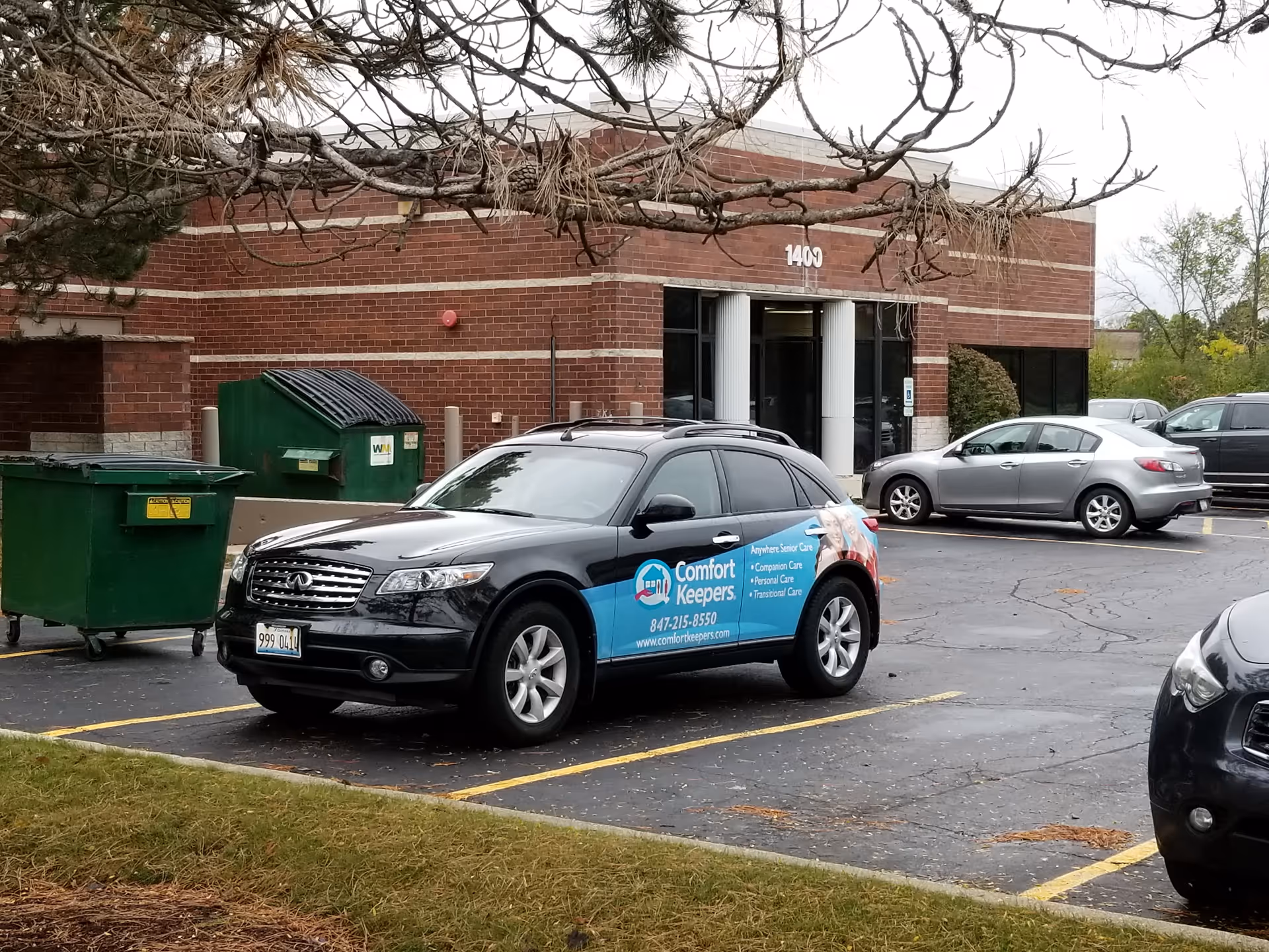 A Comfort Keepers car parked in front of a brick facility entrance.