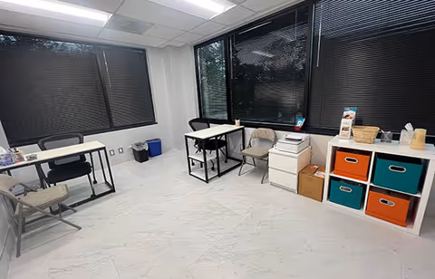 Bright, minimalist interior with desks, chairs, and colorful cubby storage along the wall.