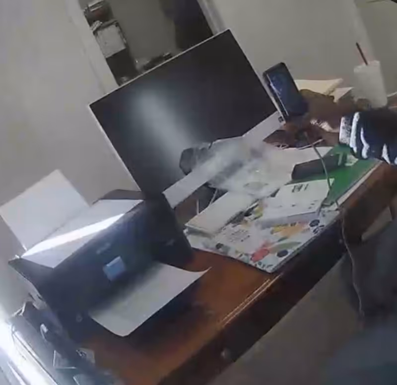Cluttered office desk with monitor, printer, papers, and supplies.