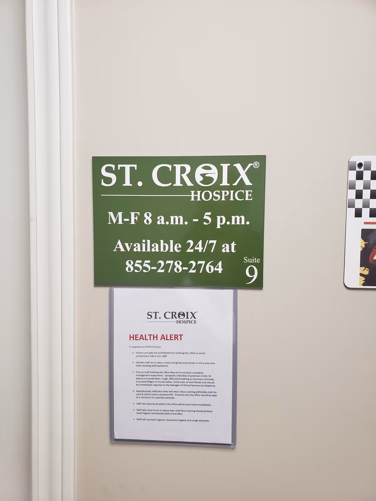 Green St. Croix Hospice sign with hours and a health alert posted on the wall.