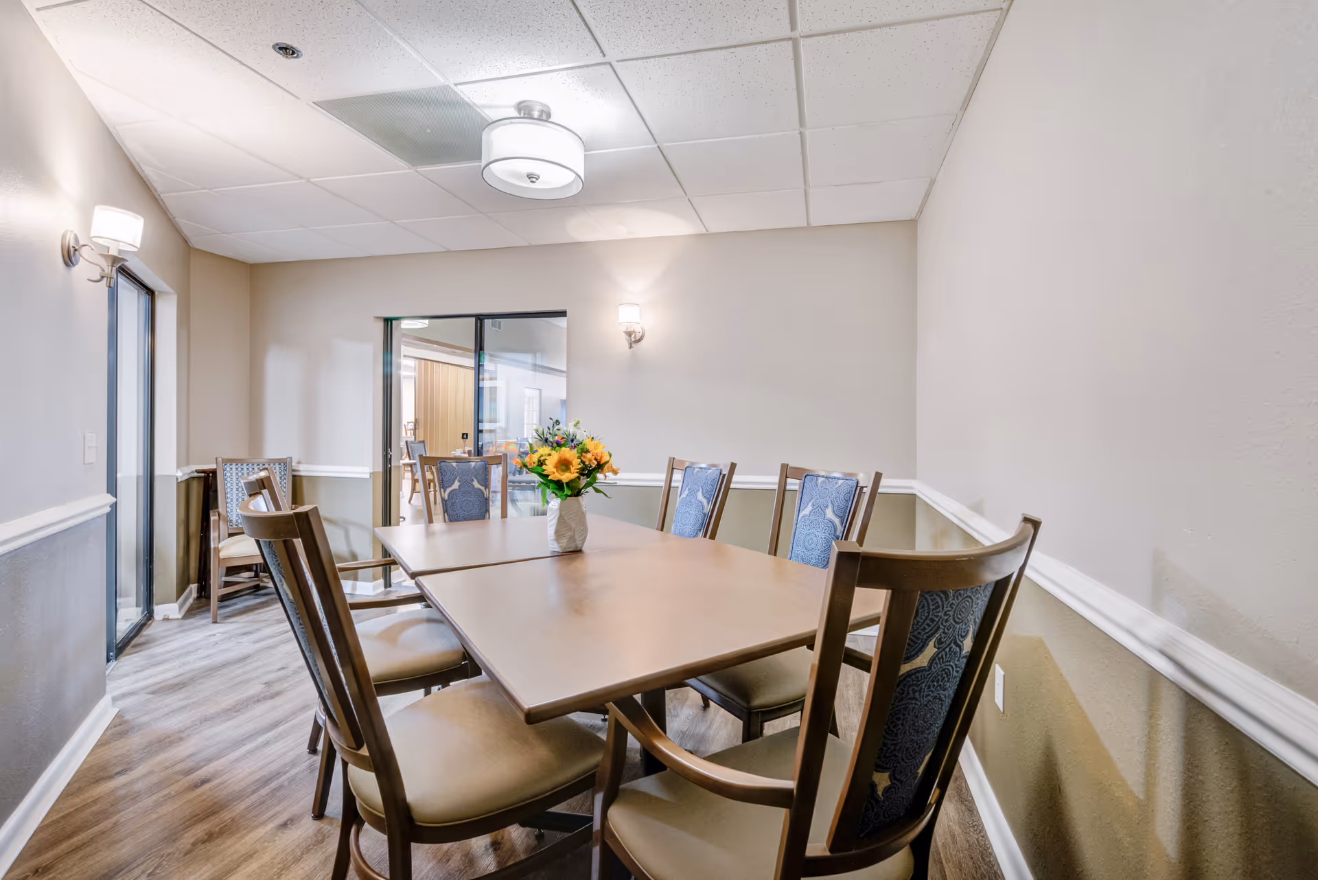 Dining room with a wooden table, chairs, and a flower vase centerpiece.