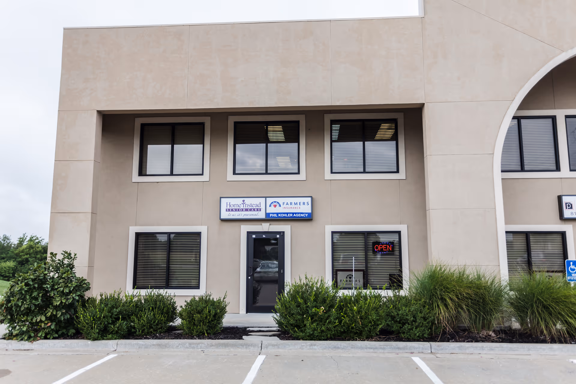 Exterior view of a beige commercial building with Home Instead signage and landscaped front.