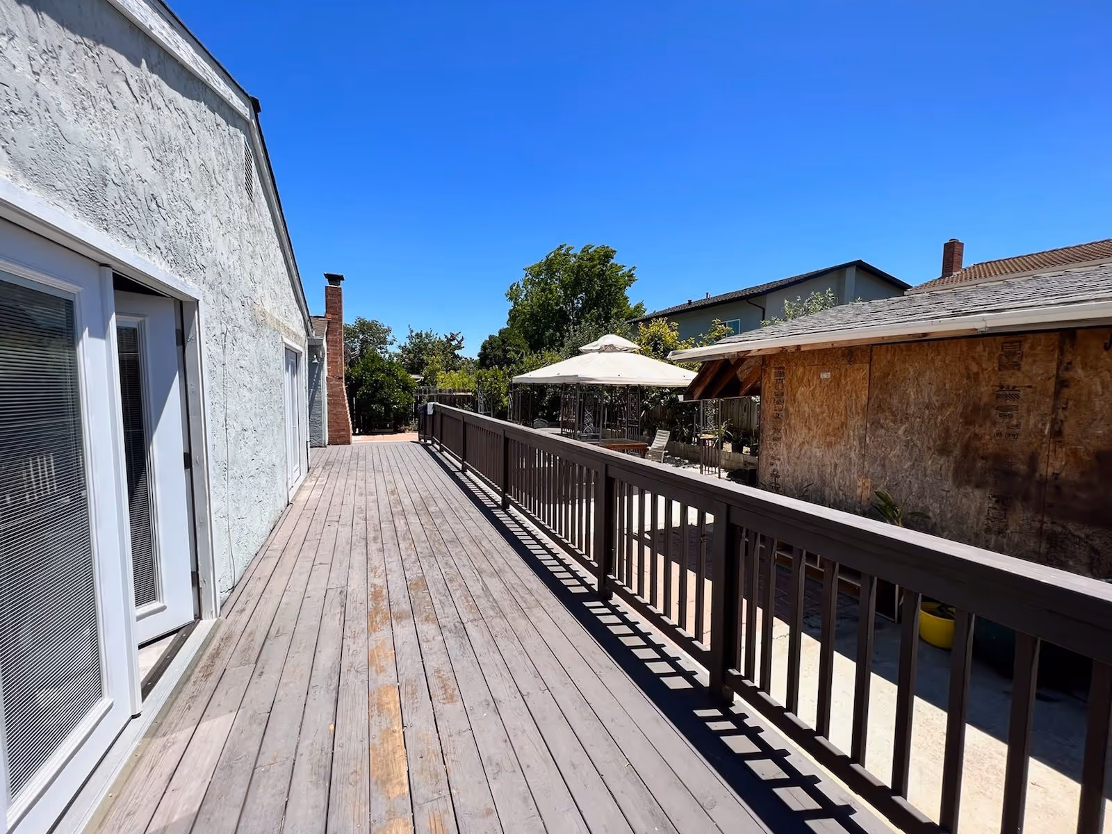 A long wooden deck with railing and umbrellas extends along a building exterior.
