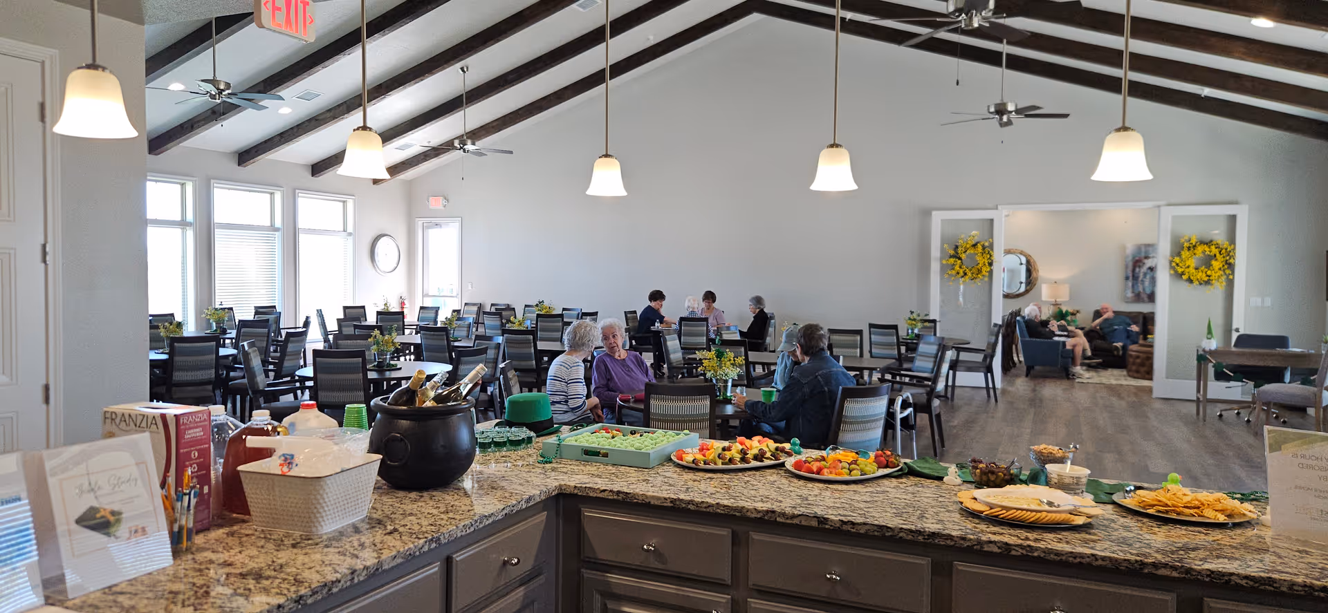 Buffet-style food setup in a bright senior dining room with residents seated.