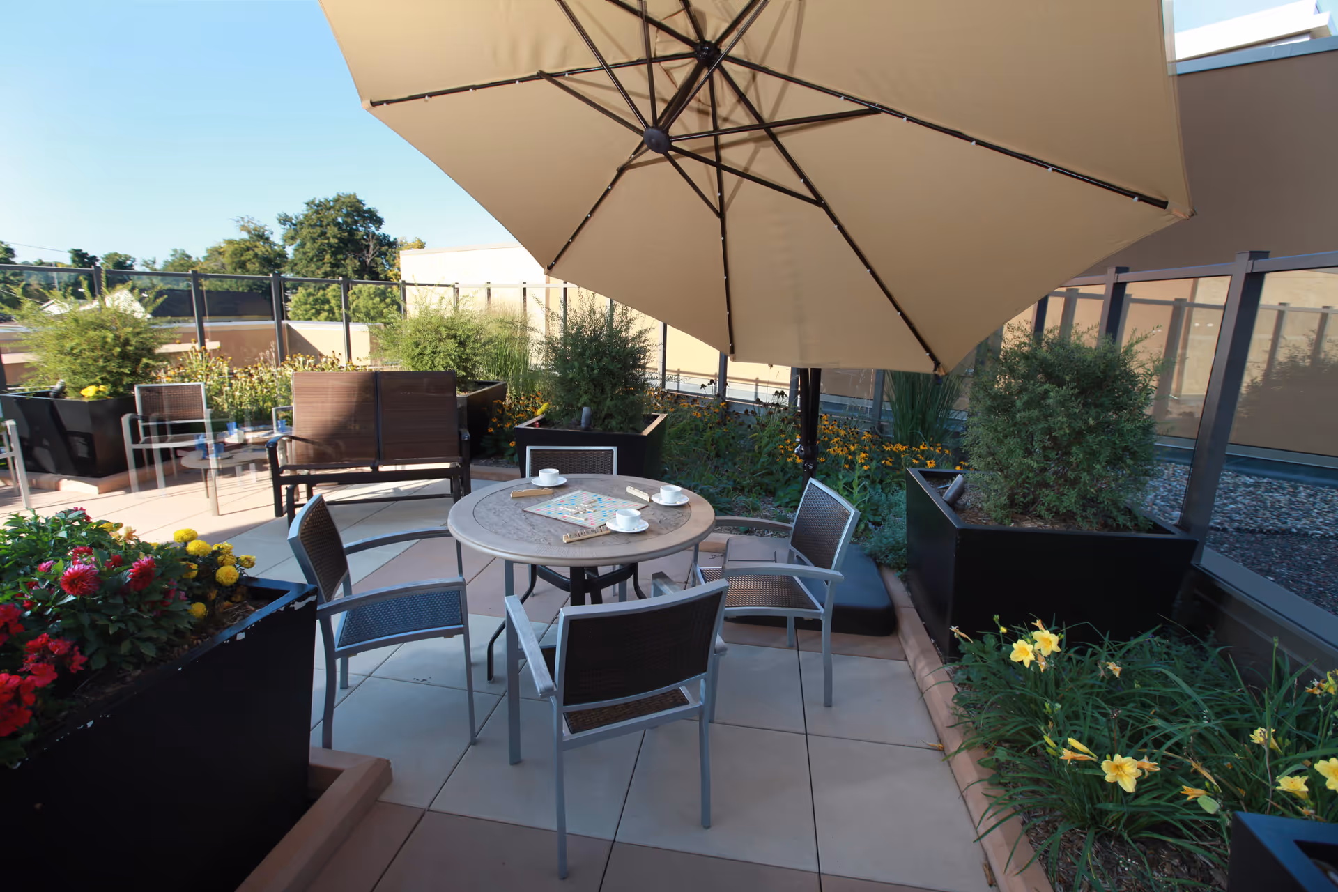 Rooftop outdoor patio with a round table, chairs, umbrella, and surrounding planters.