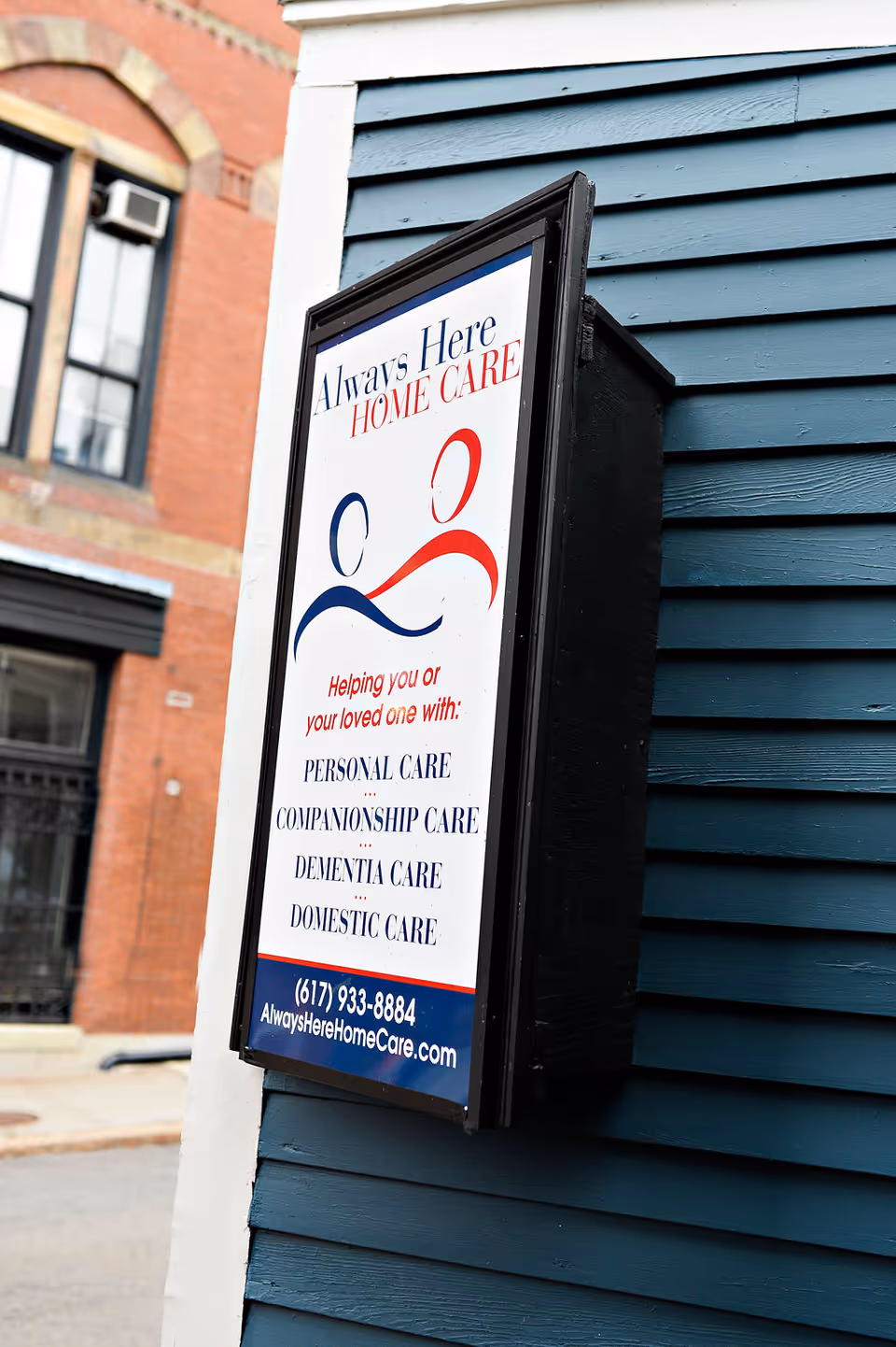 A signboard for Always Here Home Care mounted on a blue exterior wall.