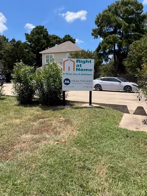 Exterior view of a Right at Home facility with sign and parked car.