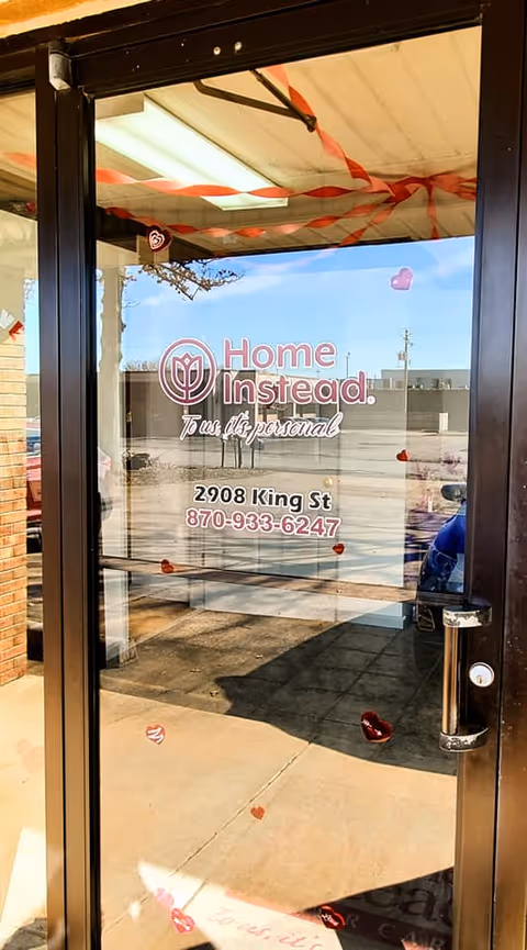 Glass entrance door with Home Instead logo, address, and red streamers.