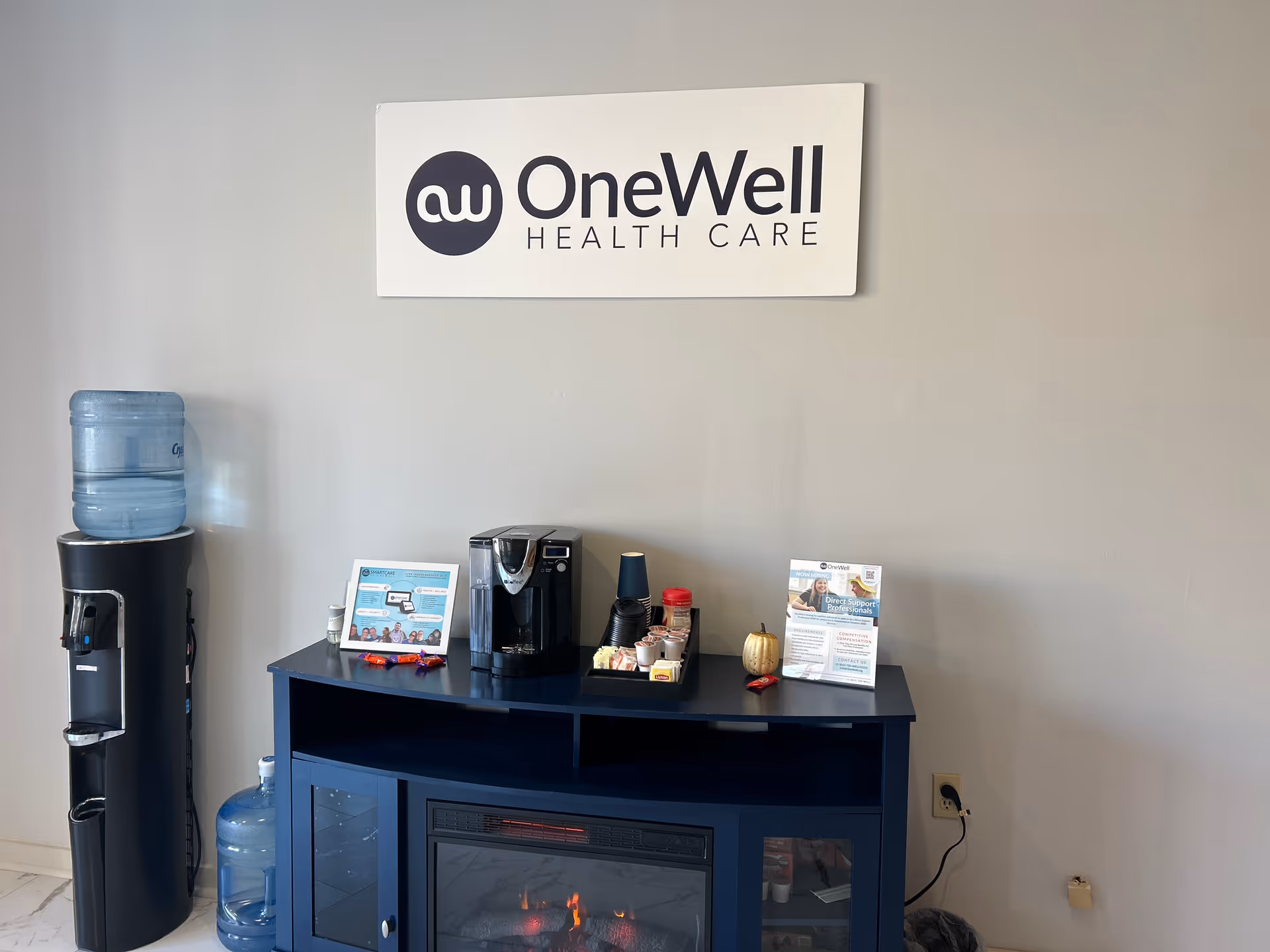 Interior reception area featuring OneWell Health Care sign, coffee bar, water cooler.