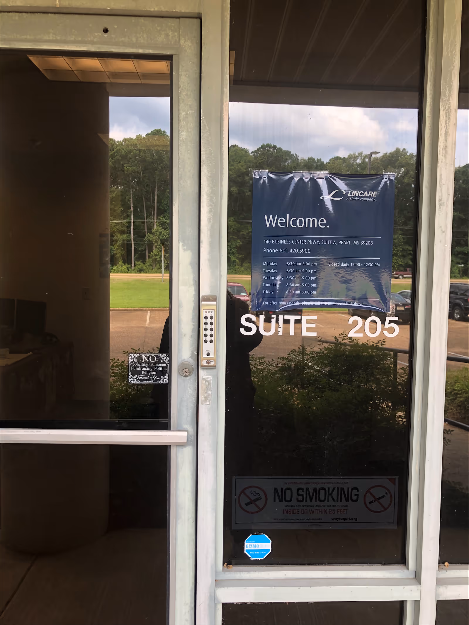Glass entrance door with 'Suite 205' and a blue welcome banner outside.