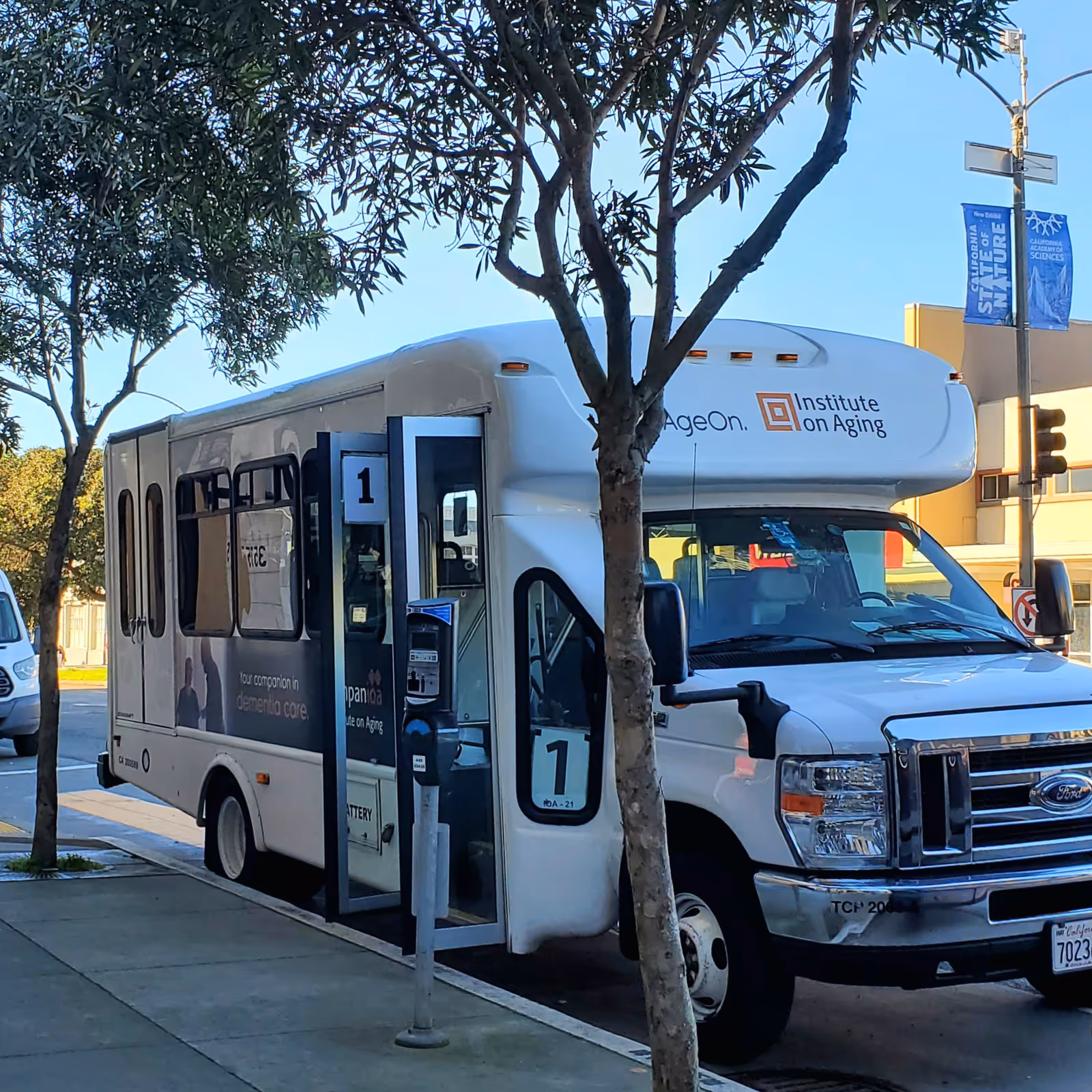 White Institute on Aging shuttle bus parked on a street beside trees.