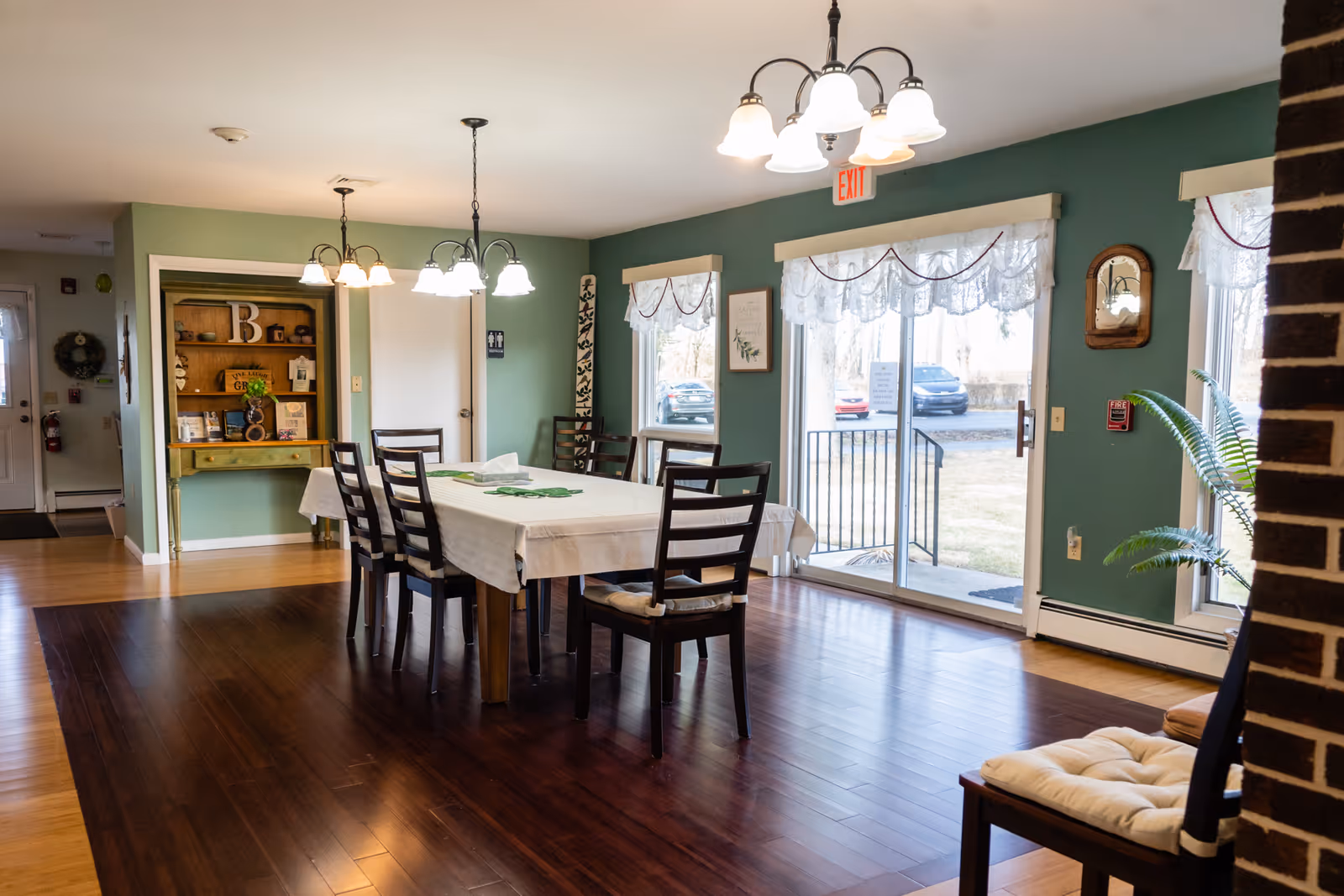 Dining room with a rectangular table, chairs, green walls, and sliding glass doors.