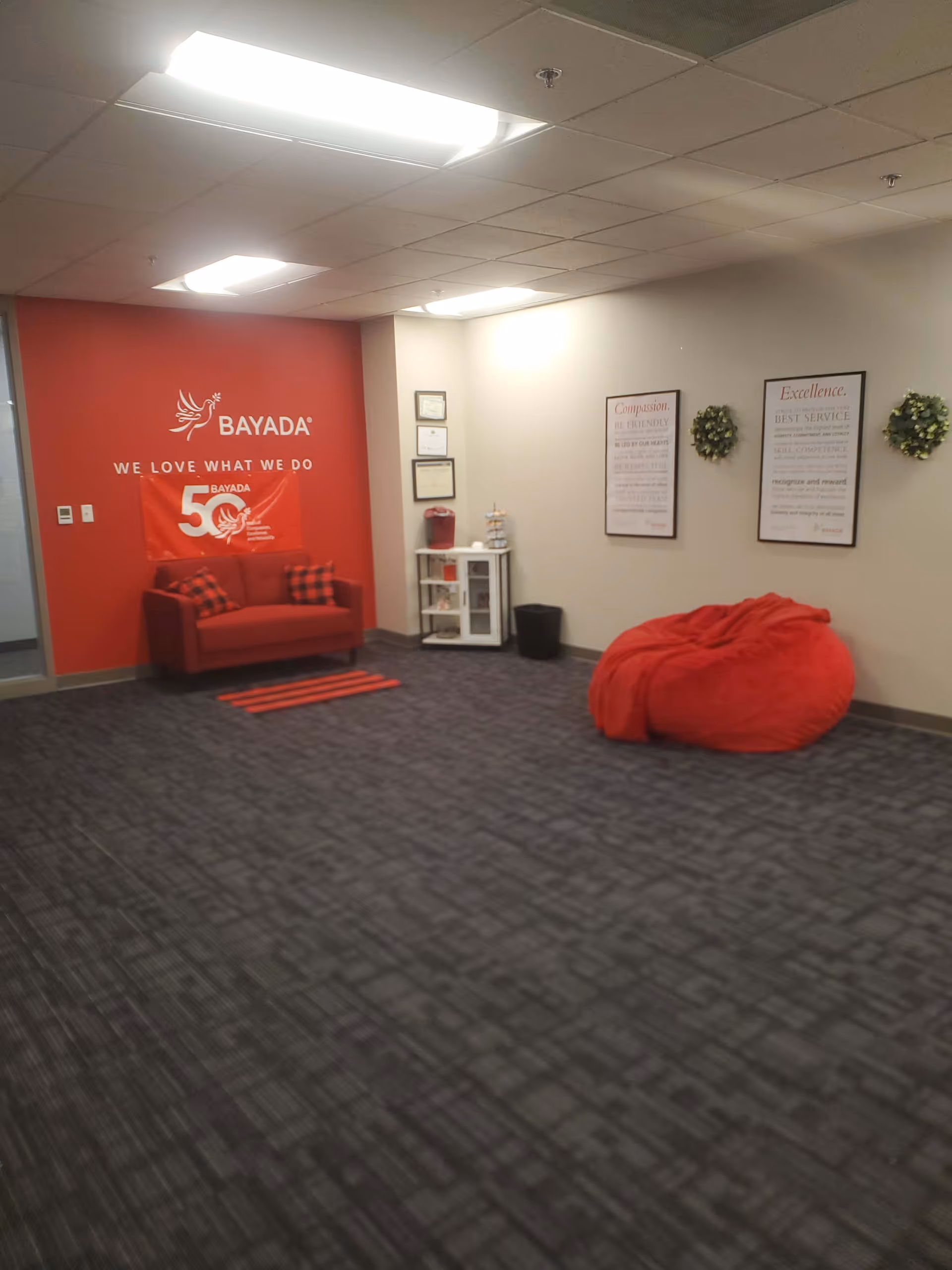 Reception area of BAYADA Hospice with a red sofa, bean bag, and framed posters.