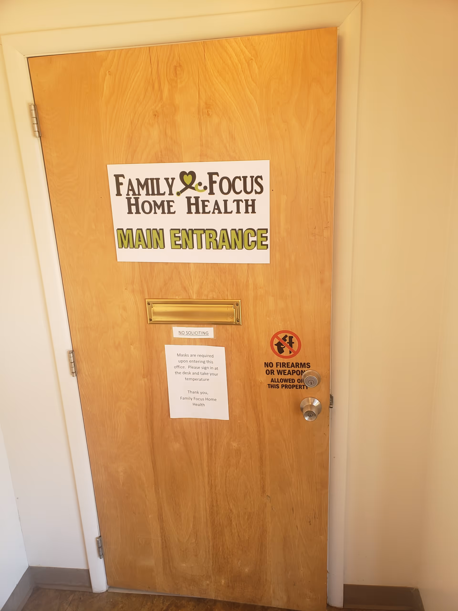 Wooden interior door with Family Focus Home Health Main Entrance sign and posted notices.