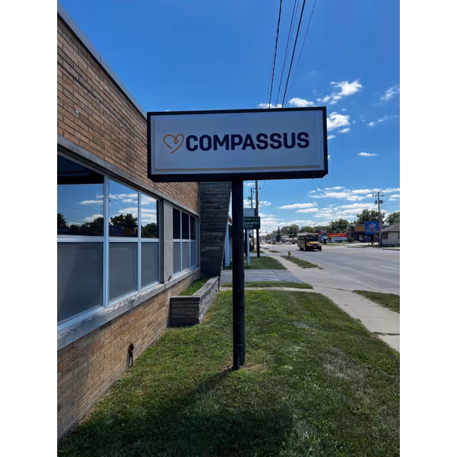 Compassus building exterior with a large sign along the street.
