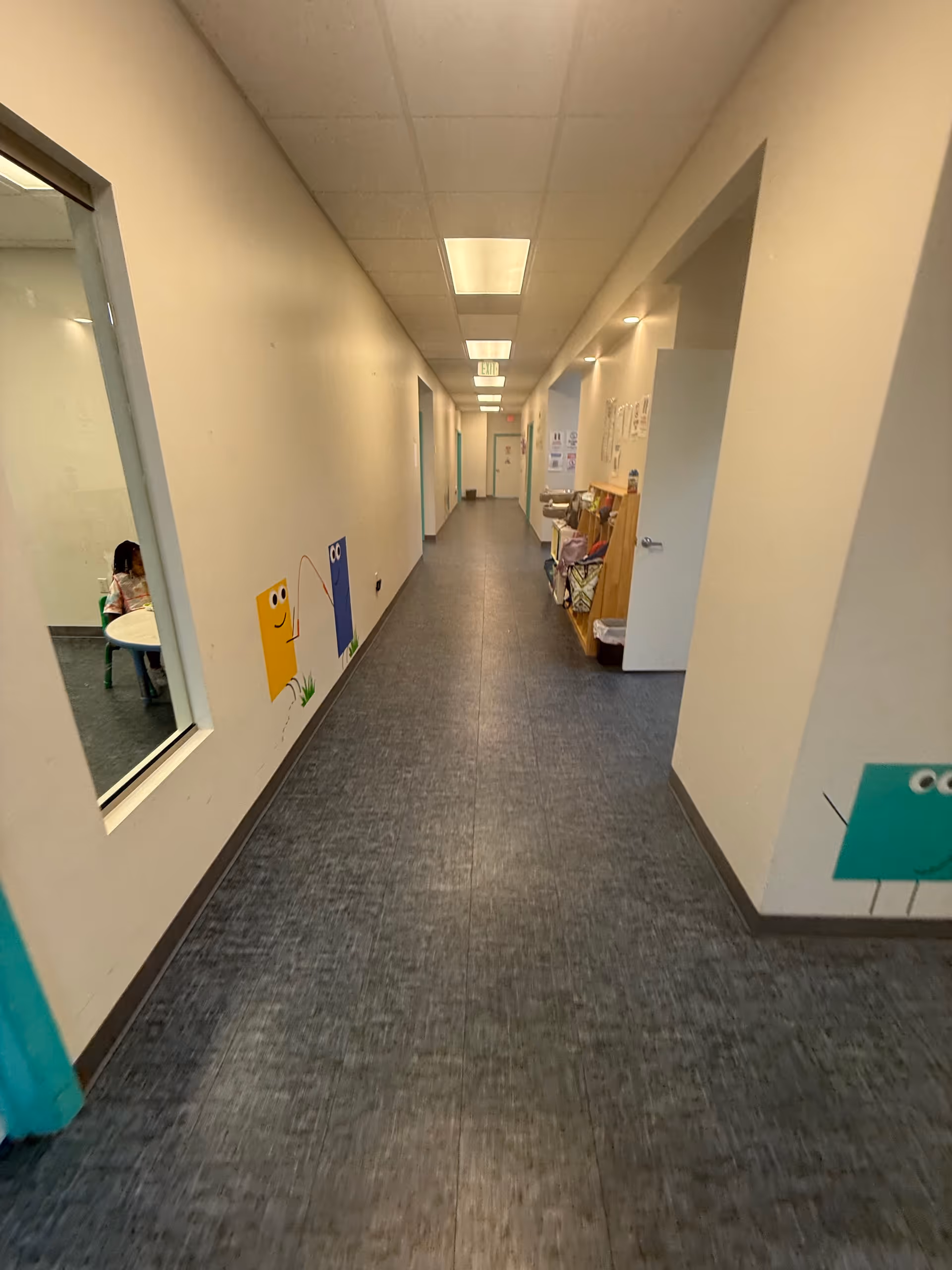 Interior hallway of a therapy center with doors and colorful wall art.
