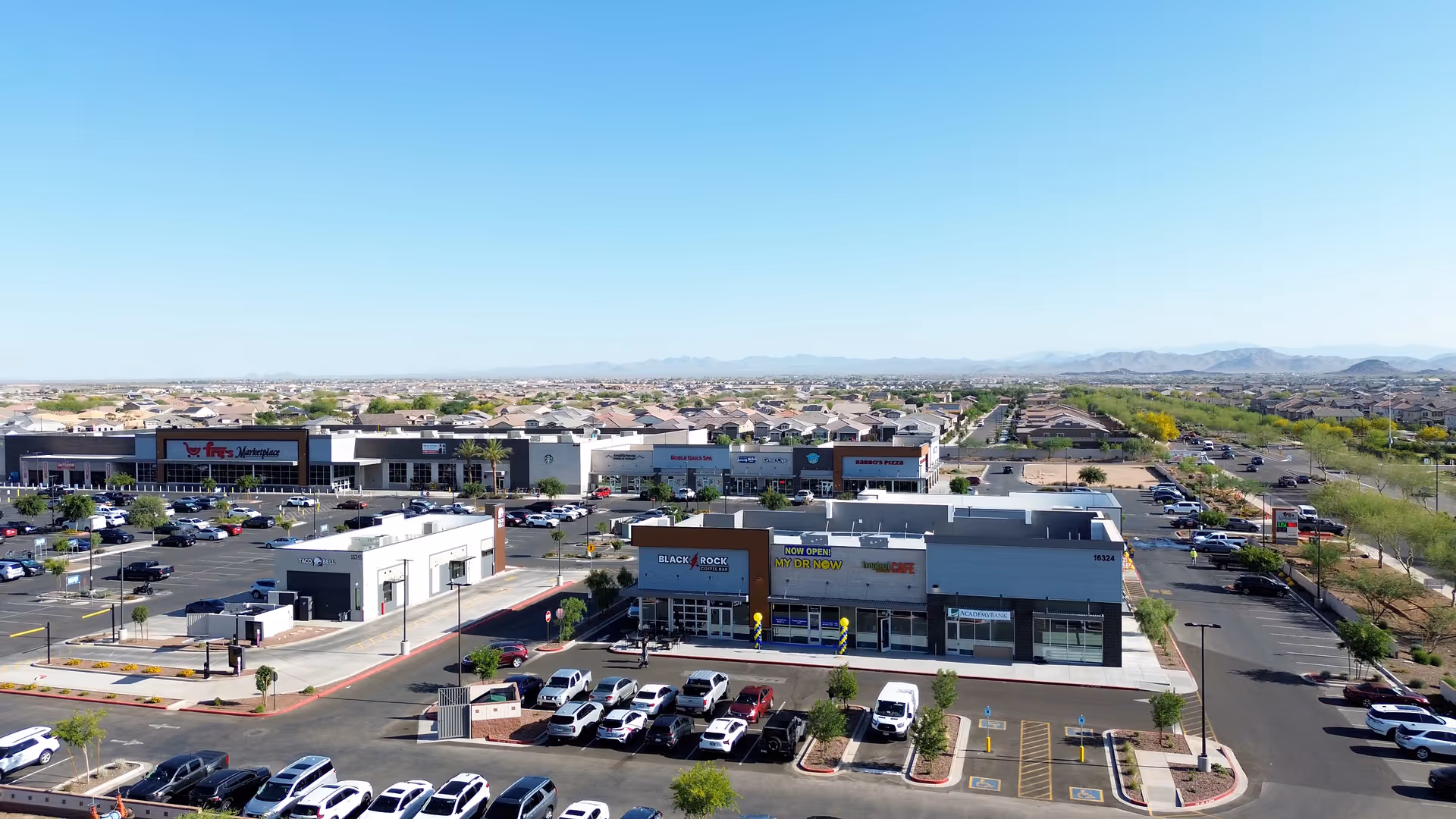 Aerial view of a shopping plaza with storefronts, including MY DR NOW on the front.