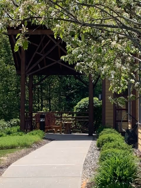 Outdoor seating gazebo at hospice facility along a paved walkway.