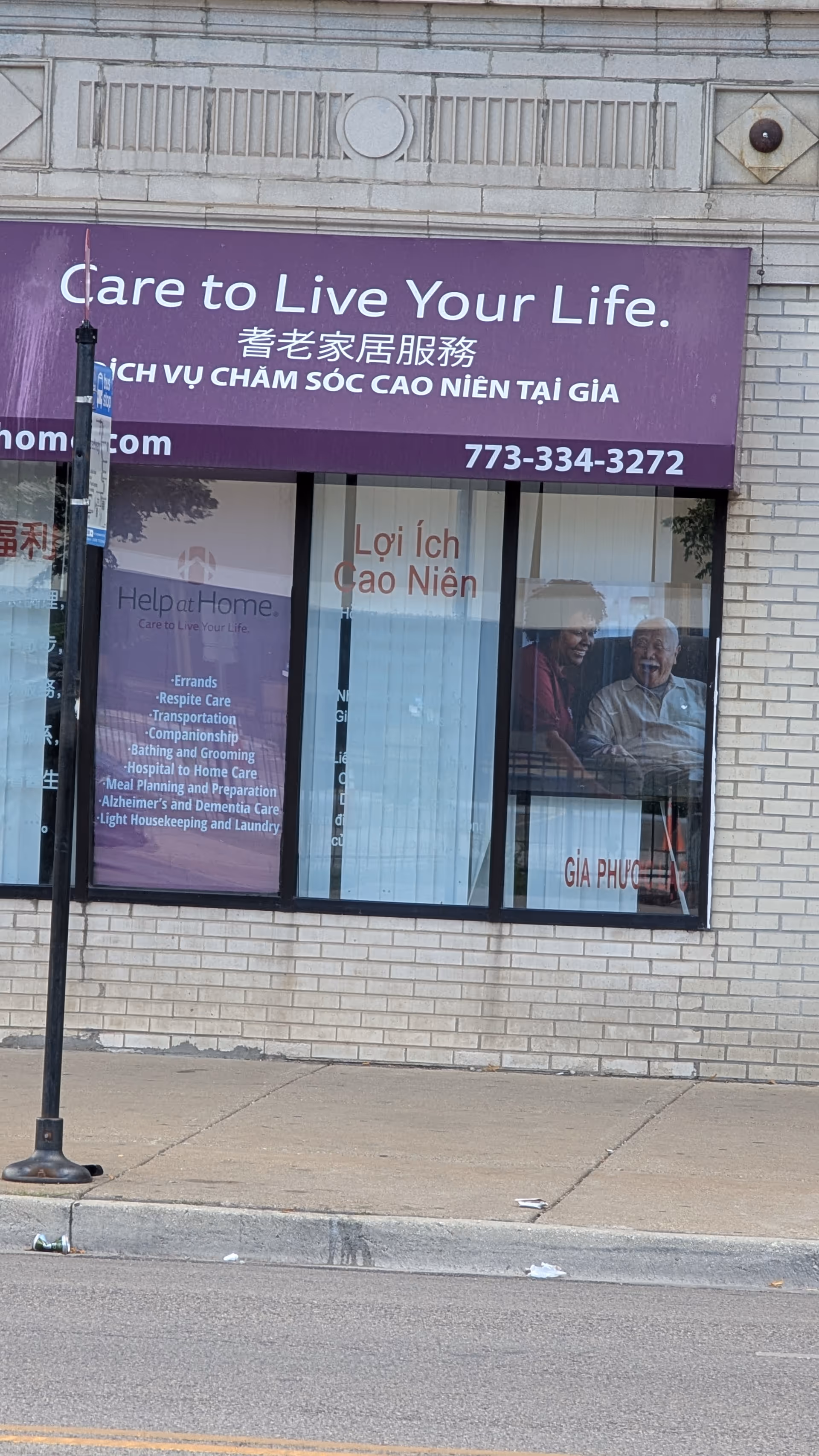Purple storefront sign reads 'Care to Live Your Life' on a brick building.