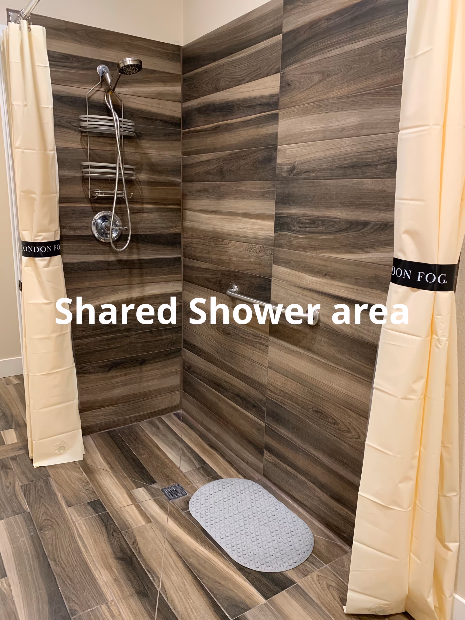 The shared shower area features wood-toned tiled walls and beige curtains.