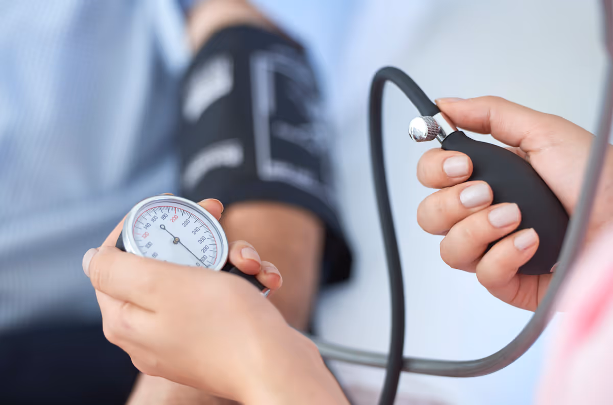 Close-up of a caregiver taking a patient's blood pressure with cuff and gauge