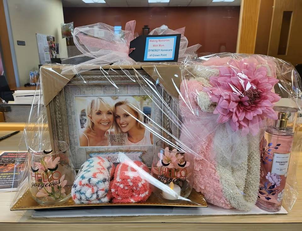 Gift arrangement with framed photo, pink towels, and flowers on a reception desk.