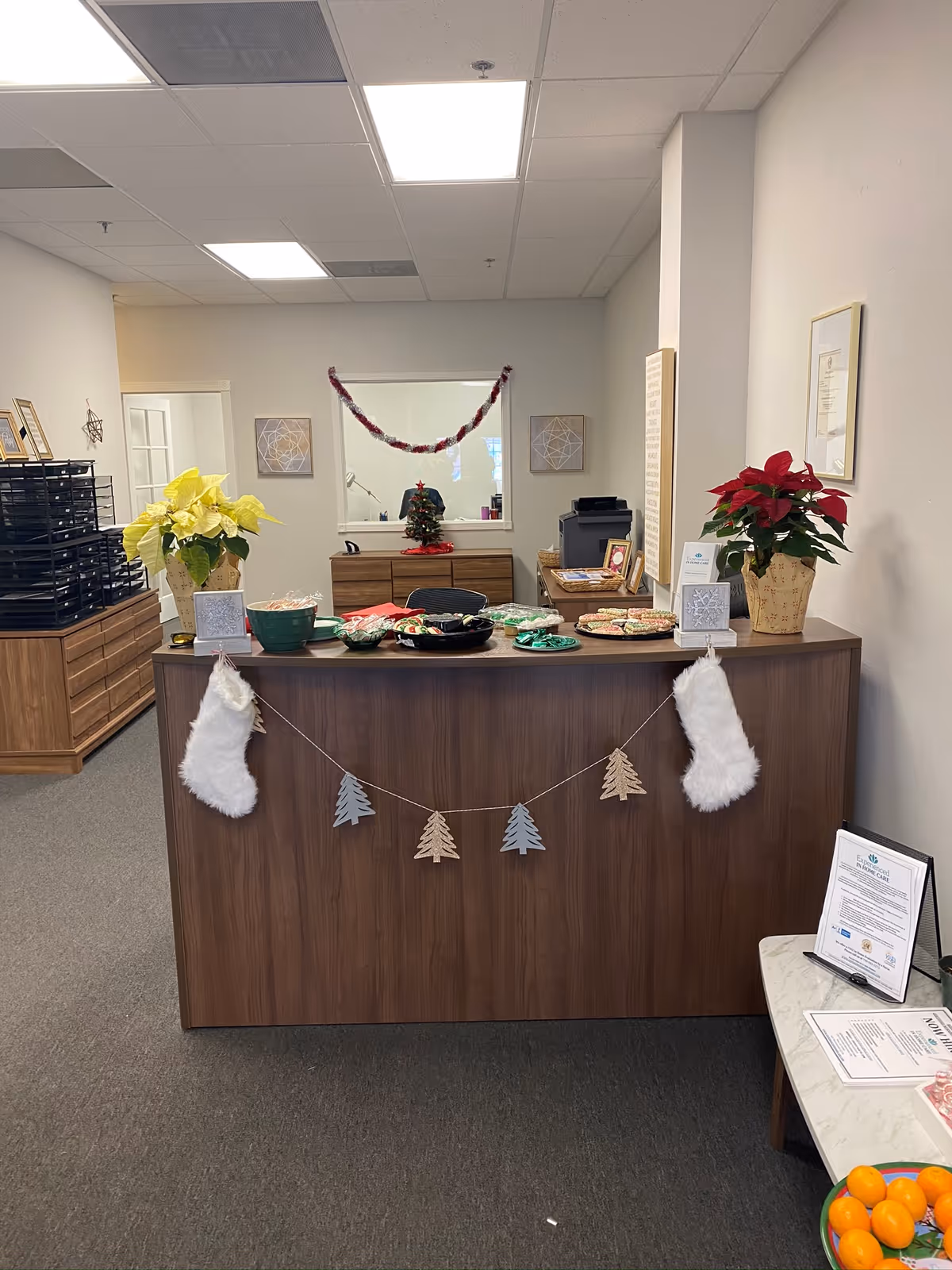 Reception desk decorated for Christmas with stockings and garlands in a hallway.