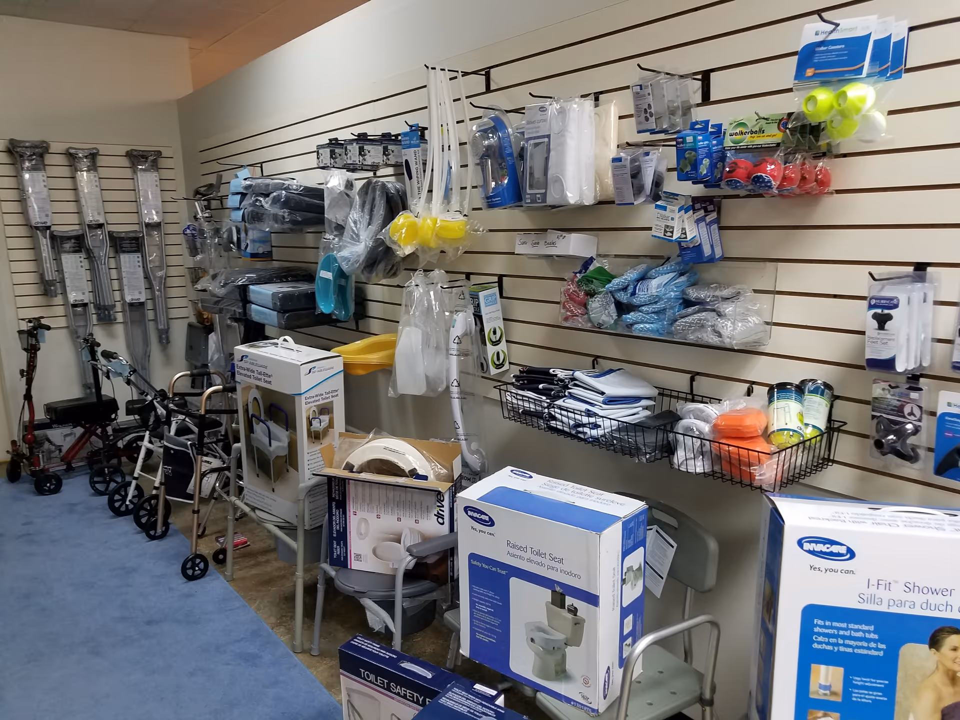 Interior supply room with walkers, shower chairs, and bathroom safety products on shelves.