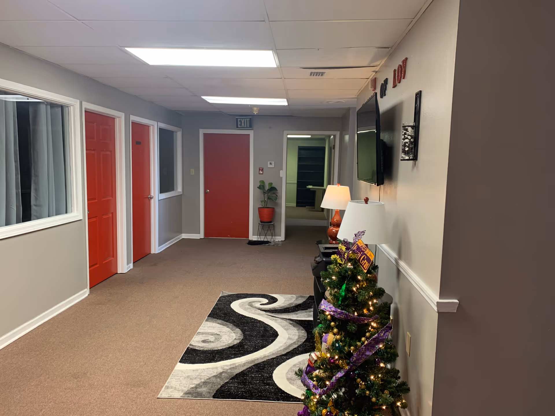 Interior hallway of a senior living facility with red doors and a Christmas tree.