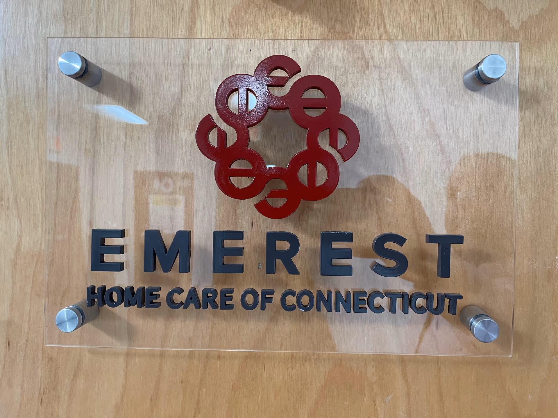 Clear acrylic sign with red circular logo and EMEREST HOME CARE OF CONNECTICUT lettering.