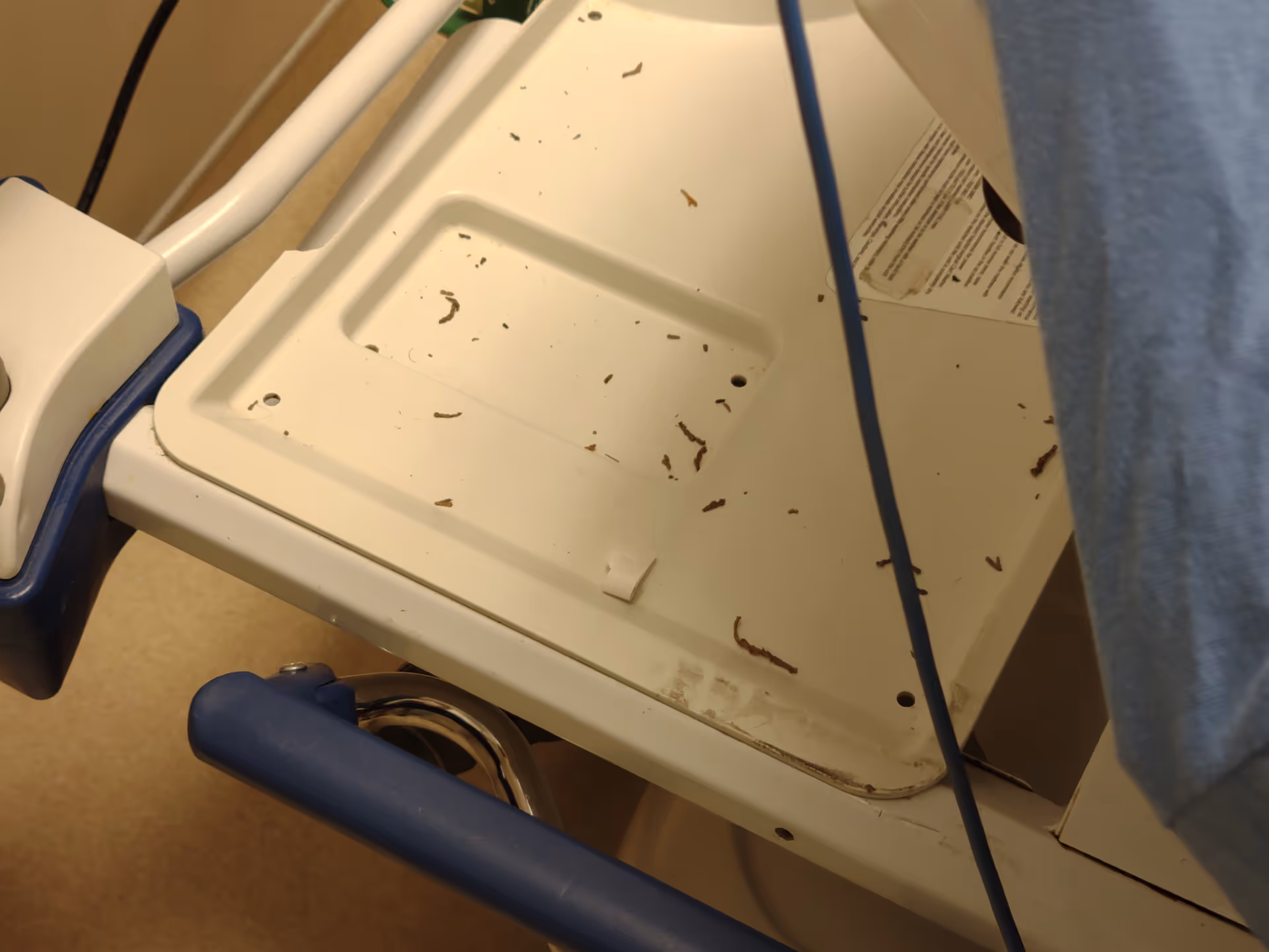 Close-up of a dirty hospital equipment tray on a patient bed inside a clinical setting.