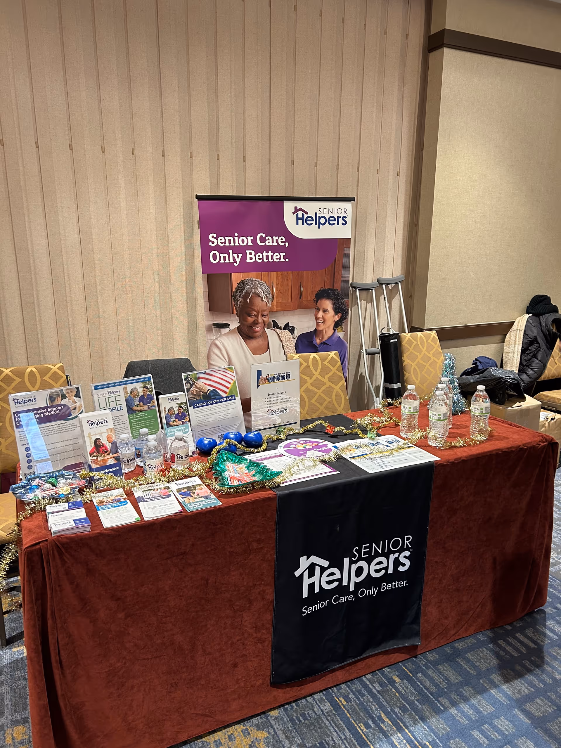 Indoor display table for Senior Helpers with brochures and banners at an event.