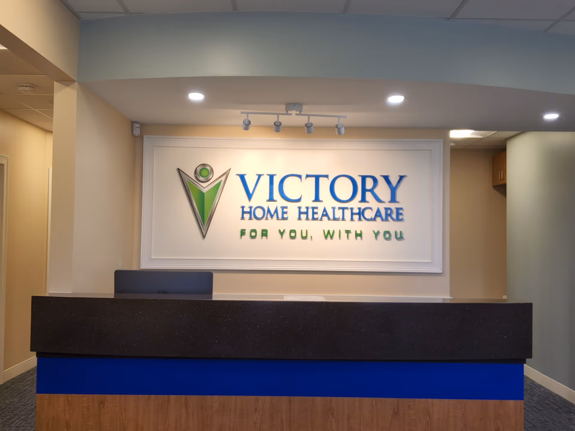 Interior reception desk with a large Victory Home Healthcare sign on the wall.