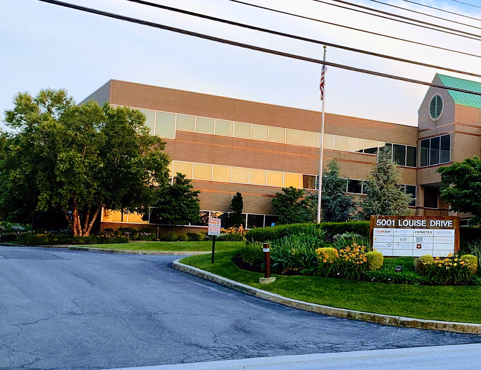 Exterior view of a brick office building with landscaping and a front sign